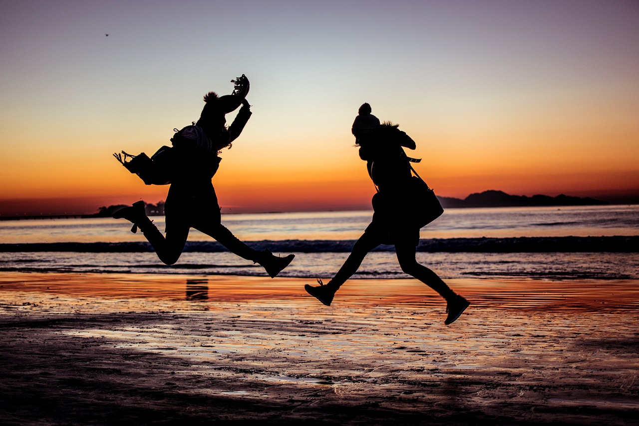 Deux femmes qui sautent sur la plage pendant un coucher de soleil